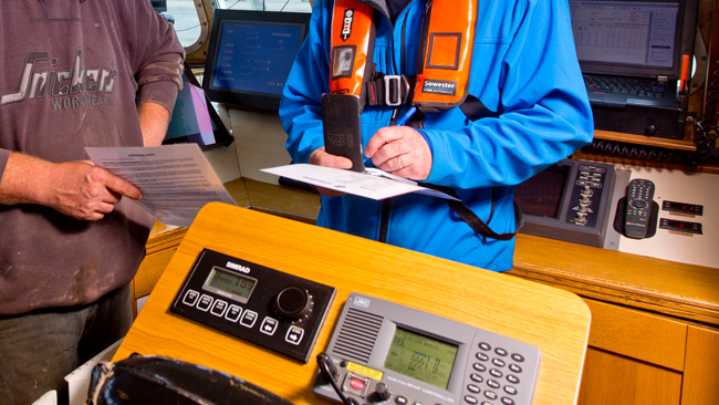 fisheries officer consulting with fisherman in wheelhouse of vessel